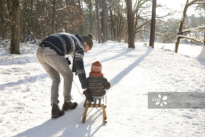 在阳光明媚的日子里，父亲在雪地上教儿子滑雪图片素材