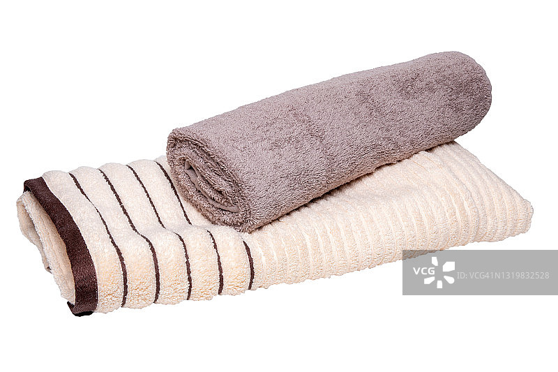 毛巾孤立。特写一堆或一堆棕色的米色软毛巾布浴巾孤立在白色的背景上。图片素材