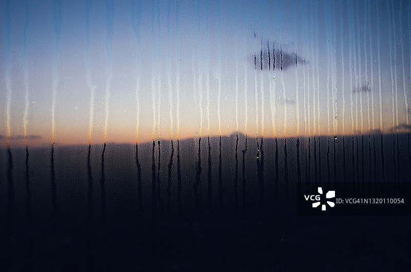 透过凝结的窗户，夕阳下的天际线勾勒出富士山的轮廓图片素材