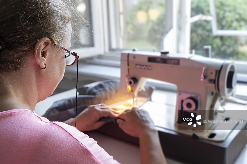 女人在家里用缝纫机，选择性聚焦图片素材