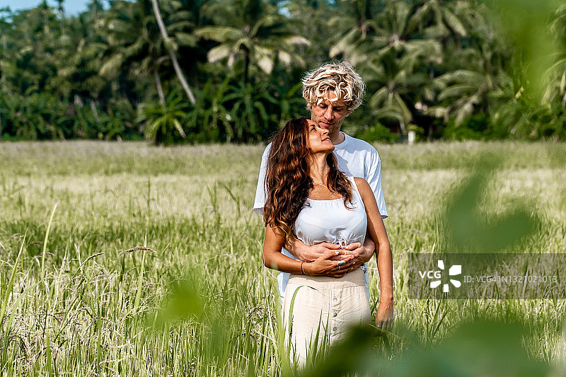 斯里兰卡，日出时分，一对幸福的情侣在草地上拥抱在一起图片素材