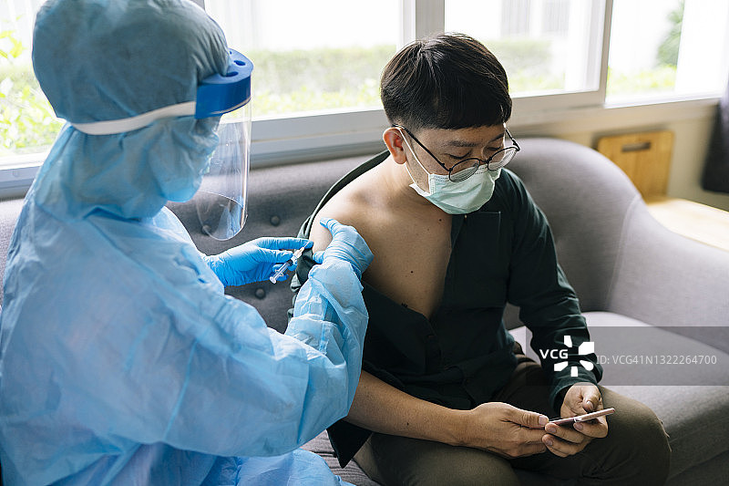 佩戴防护口罩和手术手套的医生对肩肩患者进行COVID-19疫苗(冠状病毒)接种的手密切接触图片素材