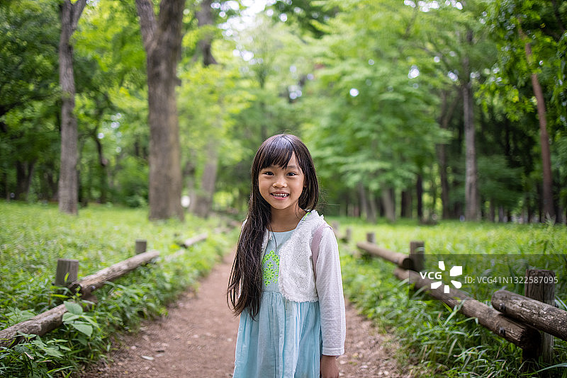 一个快乐的小女孩站在森林的小路上图片素材
