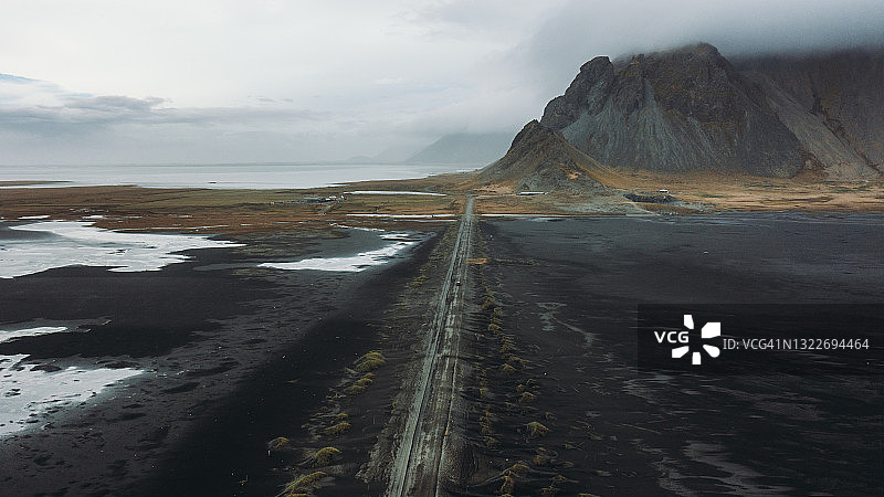 风景鸟瞰图的汽车驾驶偏僻的山路在黑沙滩沙丘在冰岛图片素材