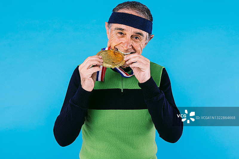 上了年纪的运动员穿着绿色和黑色的复古球衣，上面有一个大的赢家奖牌，在蓝色的背景上。图片素材