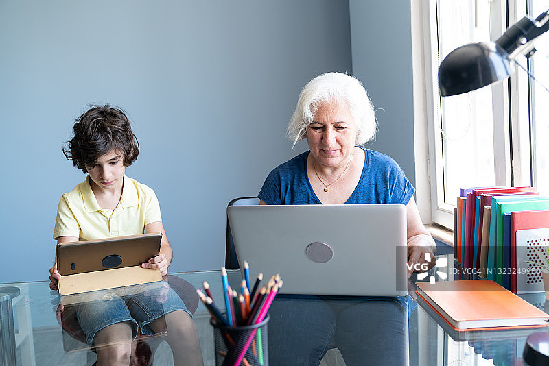 老奶奶和孙子在家里用笔记本电脑和数码平板电脑图片素材