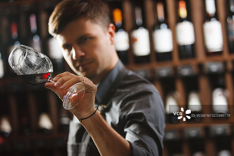 以博卡尔红酒为背景，男侍酒师品酒图片素材