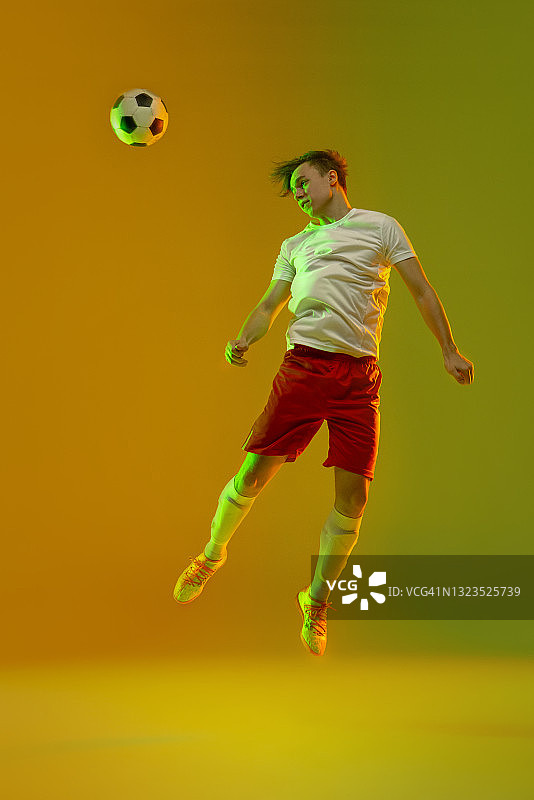 年轻的白人男子，男性足球运动员训练孤立在梯度黄绿色背景霓虹灯图片素材