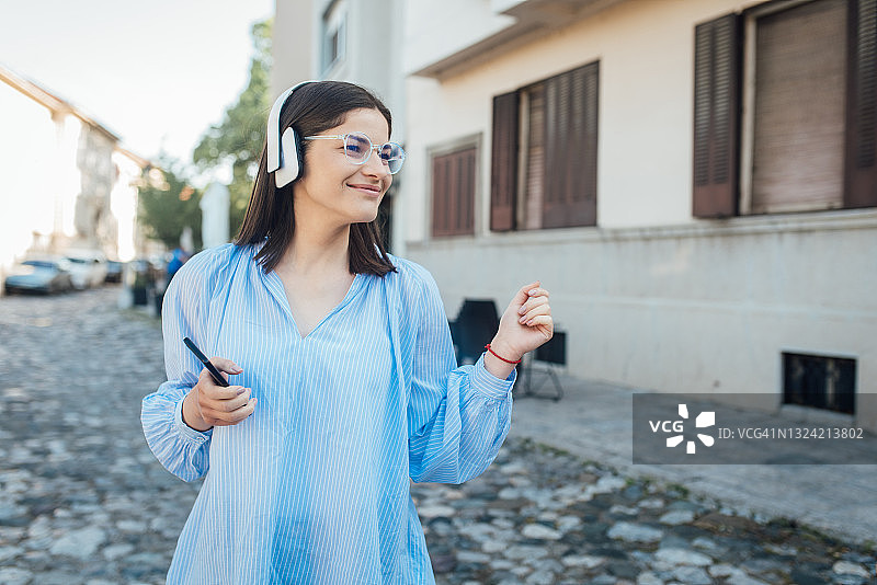 一个女孩戴着耳机听音乐和在街上跳舞的肖像图片素材
