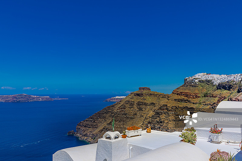 夏日全景度假，奢华著名的欧洲目的地。希腊圣托里尼岛的白色建筑。完美的旅游风景，粉红色的花朵和游轮在阳光和蓝天。惊人的观点图片素材