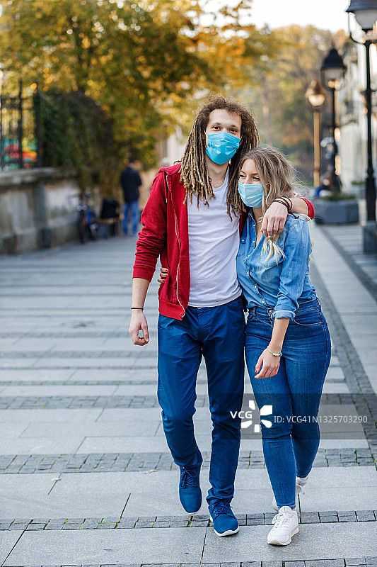 幸福的年轻夫妇一起在城市街道上度过一个美好的秋天，亲吻和拥抱。图片素材