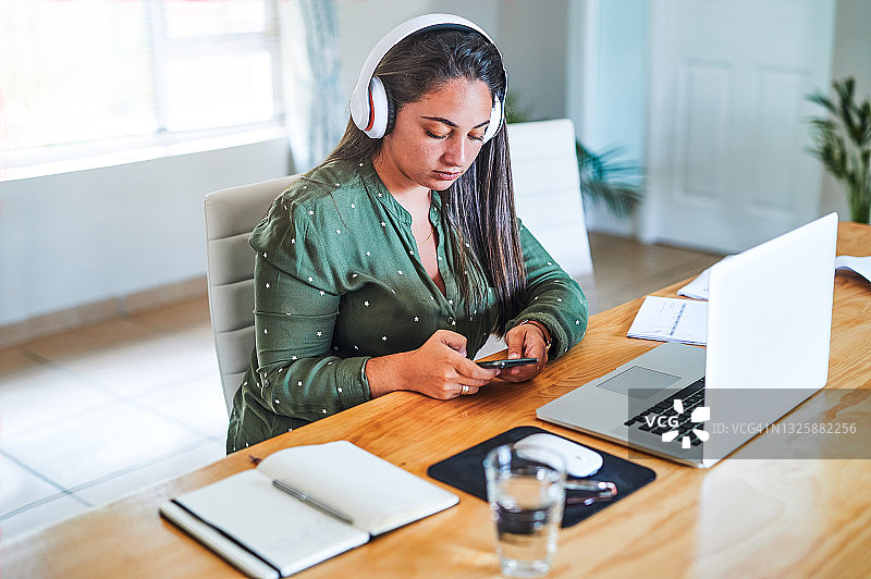 一名年轻女子在工作时戴着耳机听音乐图片素材