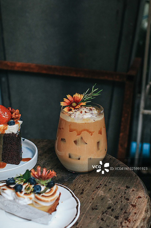 冰焦糖拿铁咖啡加糖浆和鲜奶油装饰花。在复古风格的咖啡店休息图片素材
