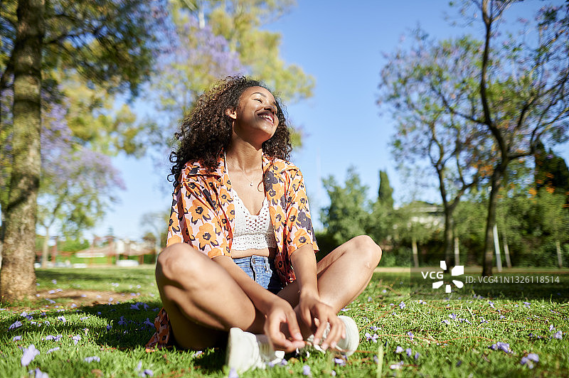 一个年轻女子盘腿坐在公园里图片素材