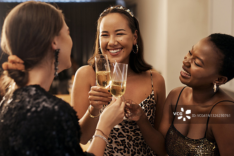 在新年晚宴上，一群不同的朋友站在一起，用香槟干杯图片素材