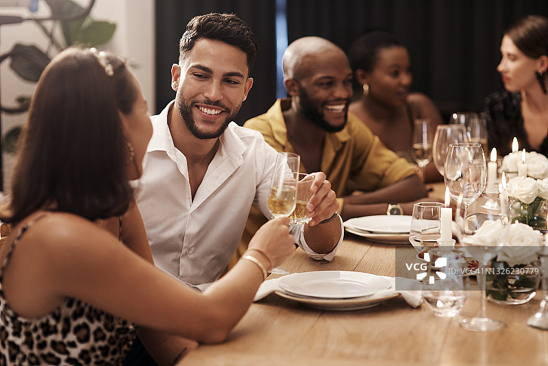 在新年晚宴上，一对幸福的年轻夫妇和朋友坐在一起，喝着香槟图片素材