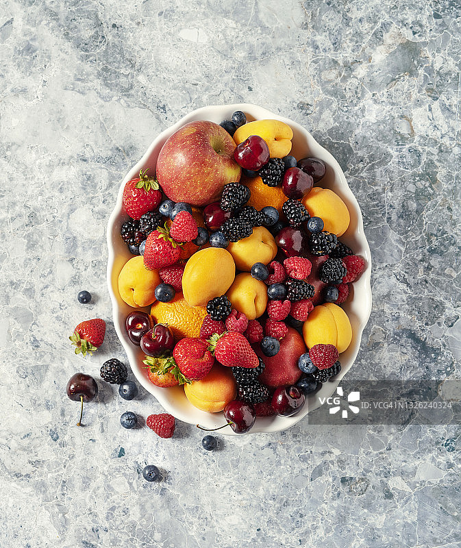 各种新鲜水果在石碗上，灰色背景图片素材