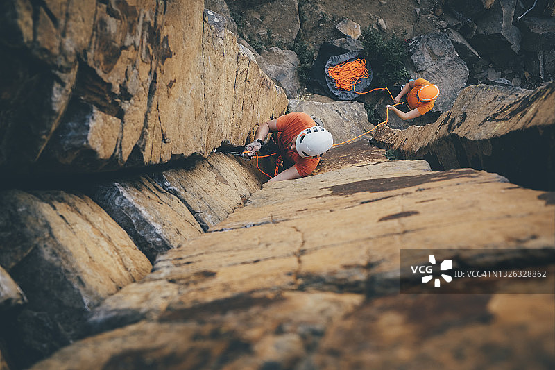 头顶上的照片是一位男性攀岩者在带领着一根玄武岩柱攀爬时夹着他的攀岩绳图片素材