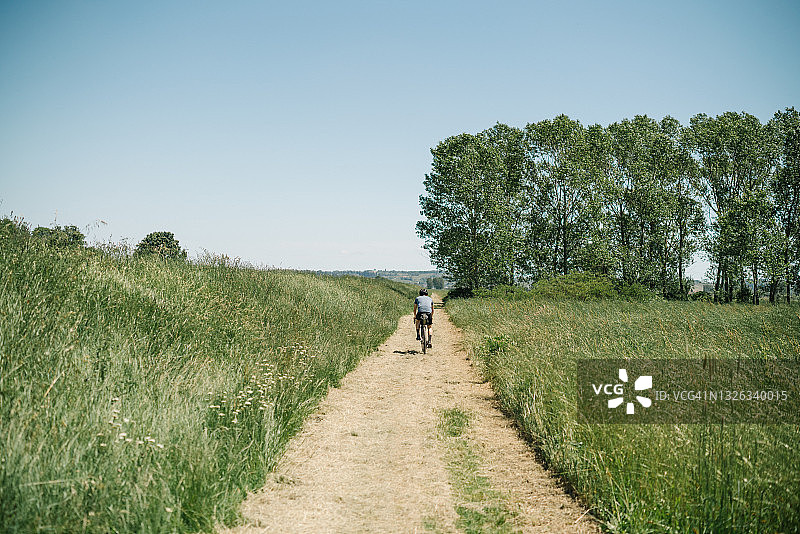 一个年轻人骑着自行车穿过托斯卡纳乡村图片素材