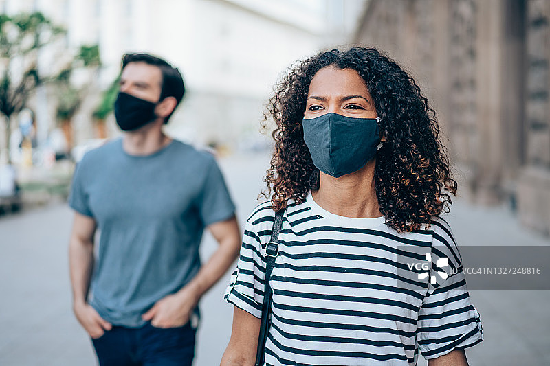 戴着防护口罩在城市户外行走的人们。图片素材