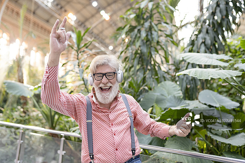 快乐成熟的男人戴着眼镜在植物前跳舞图片素材