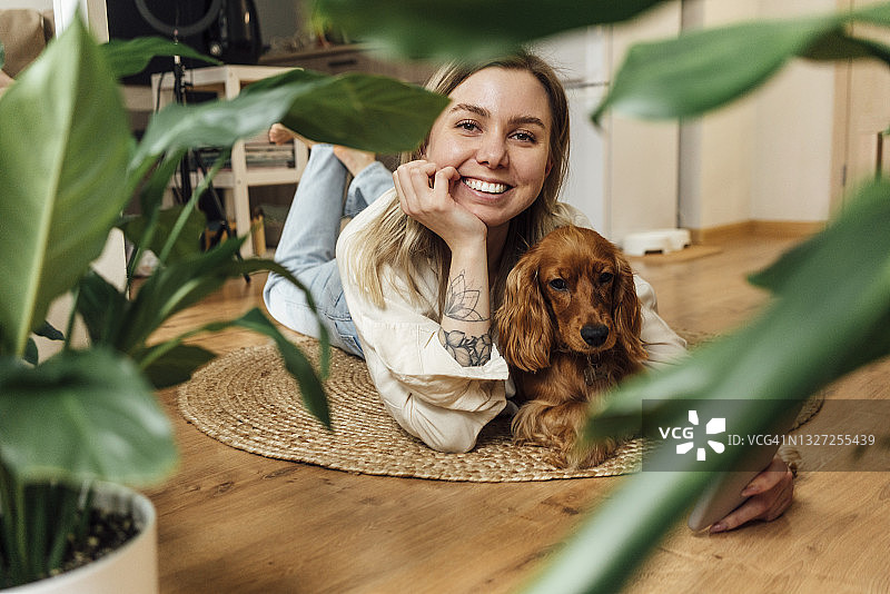 微笑的女人和狗躺在家里的客厅图片素材