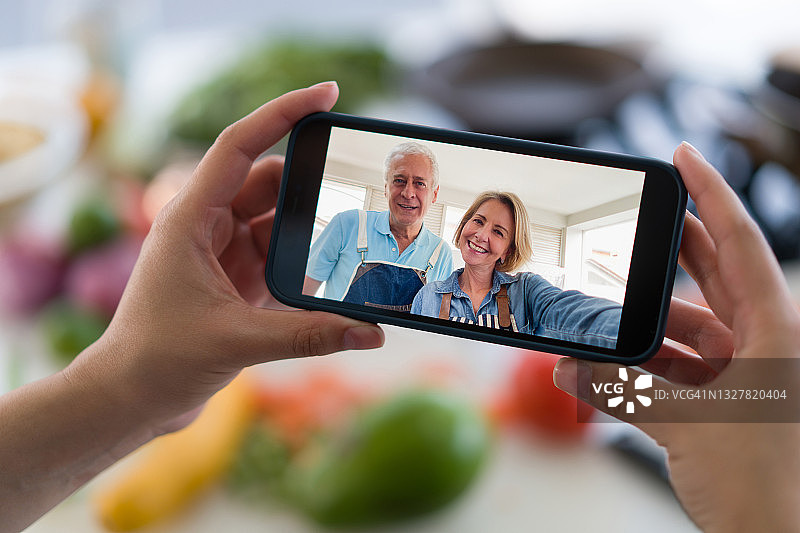 一个女人在做饭时接听父母的视频电话的特写图片素材