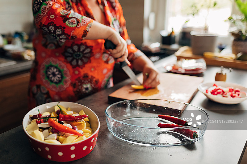 一个健康的女人，在她的现代厨房里切她的素食菜图片素材