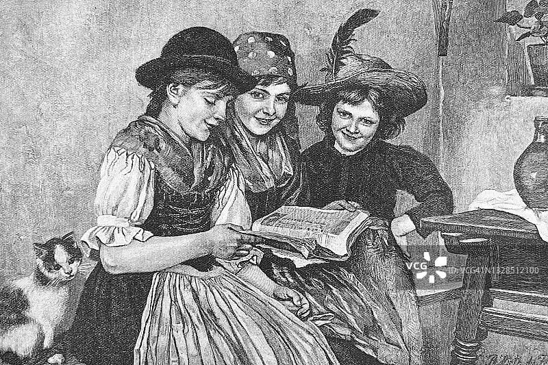 三个女孩在看杂志，开心地笑着图片素材