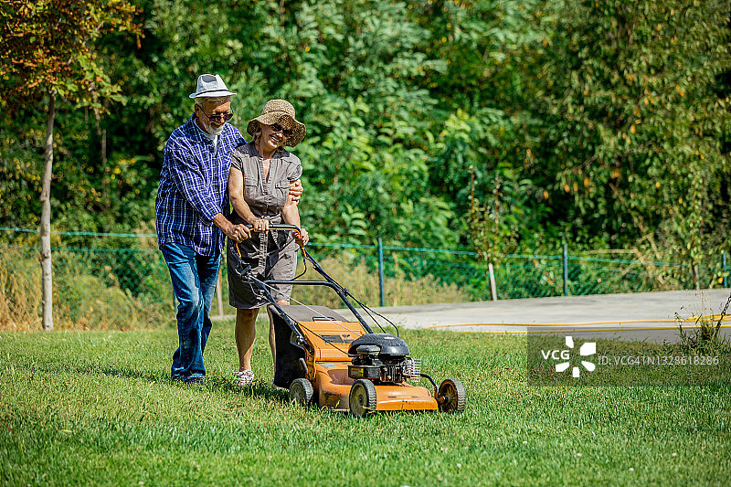 一对老夫妇在前院修剪草坪图片素材