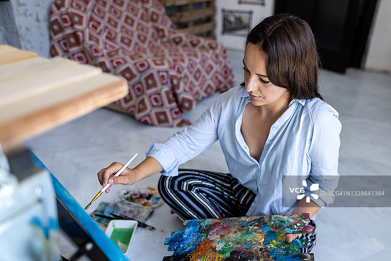 年轻的女艺术家在她的艺术工作室工作的新绘画图片素材