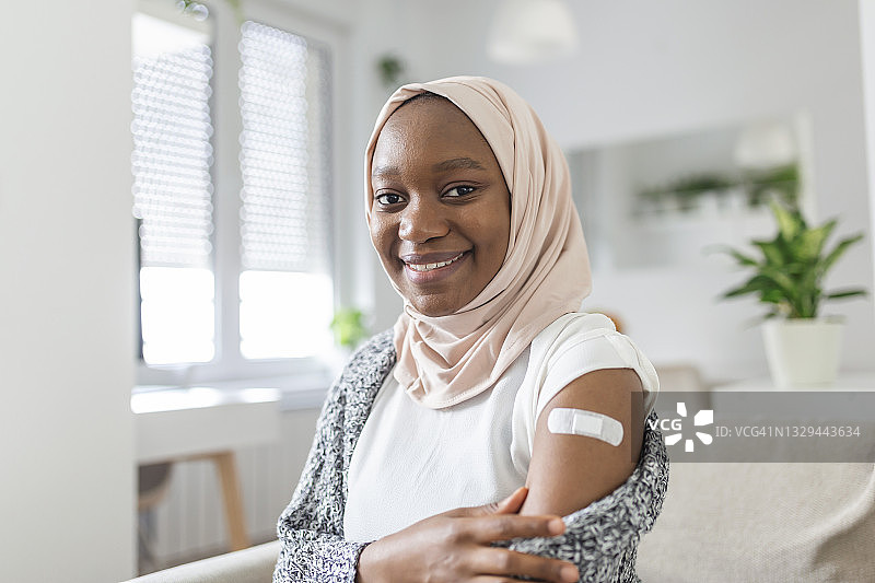 covid-19疫苗或药物注射后手臂上的粘胶绷带，粘胶绷带石膏-医疗设备，软焦点，covid-19疫苗接种后非洲穆斯林女性臂上的粘胶绷带图片素材