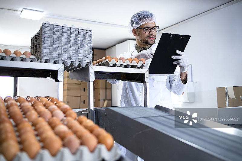 技术人员持有检查表，在食品加工厂检查鸡蛋的质量。图片素材