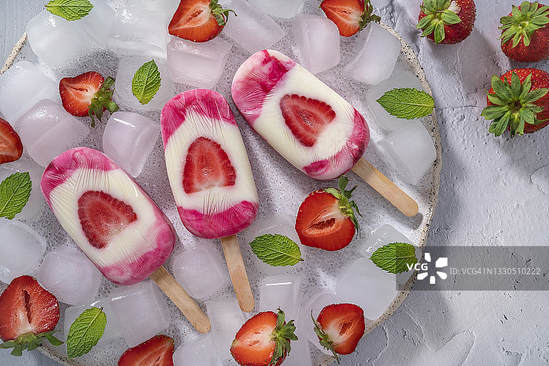 草莓手工冰棒，薄荷叶放在冰块上，白色盘子，白色背景图片素材