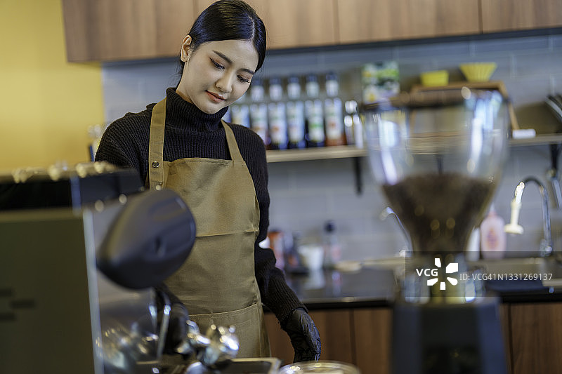 年轻女性女咖啡师为顾客在咖啡馆。图片素材