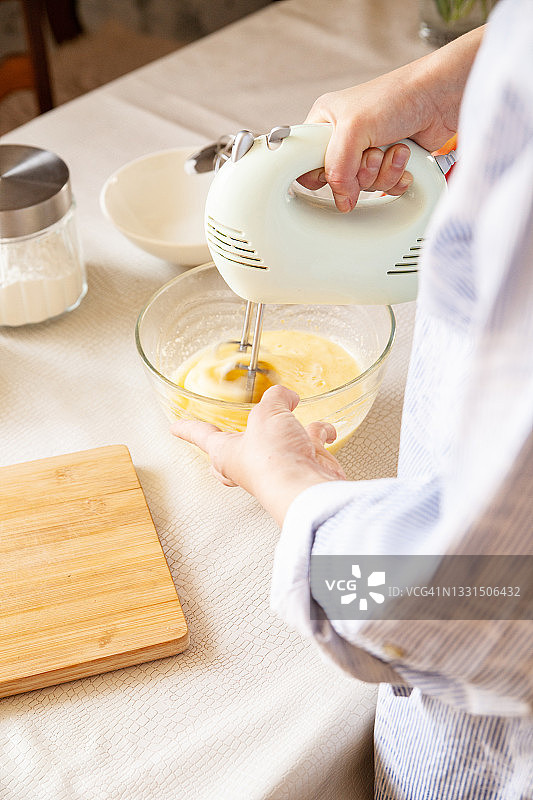 一个不知名的女人在碗里搅拌原料，准备面团图片素材