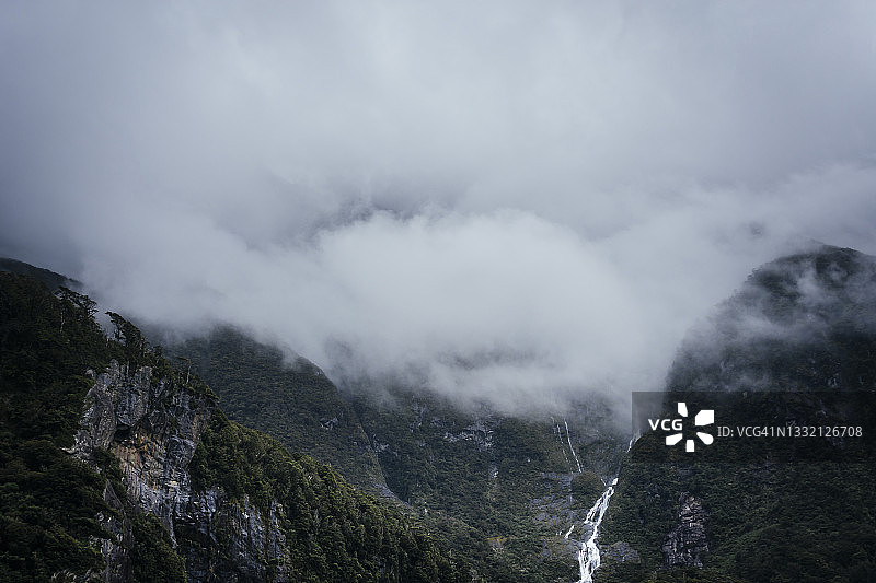 新西兰米尔福德湾，森林覆盖的峡湾和瀑布上空的低云图片素材
