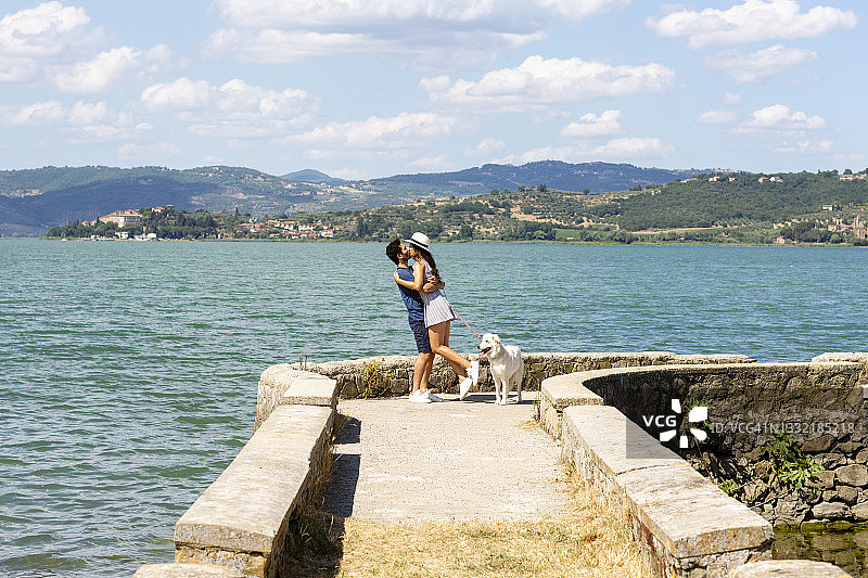 一对情侣站在特拉西梅诺湖畔的码头上接吻图片素材