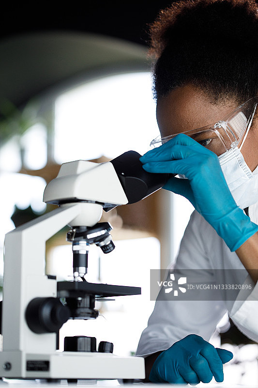女科学家穿着防护服在显微镜下观察图片素材