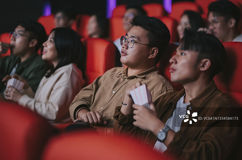 亚裔华人混合年龄段观众观看电影，在电影院排排坐欣赏电影图片素材