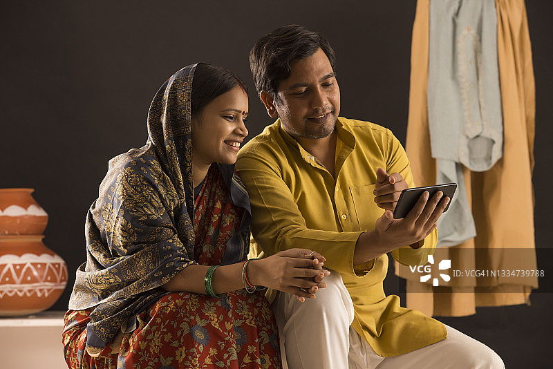 一对幸福的农村夫妇坐在一起用手机图片素材