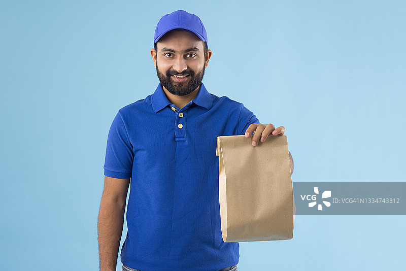 一个留着胡子的年轻送货员手里拿着包装好的食物图片素材