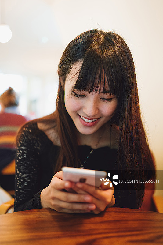 亚洲美女在咖啡馆里用智能手机图片素材