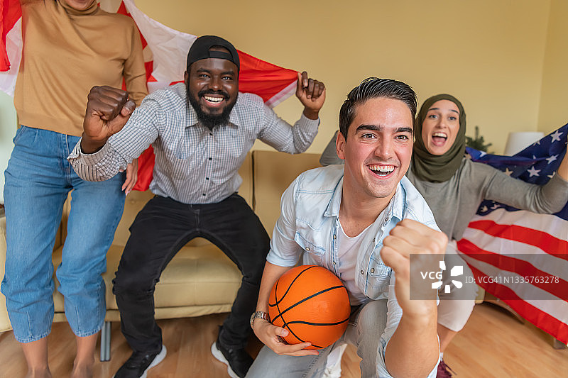 一群快乐的美国和加拿大的年轻朋友正在一起度过美好的时光，在家里看篮球比赛。图片素材