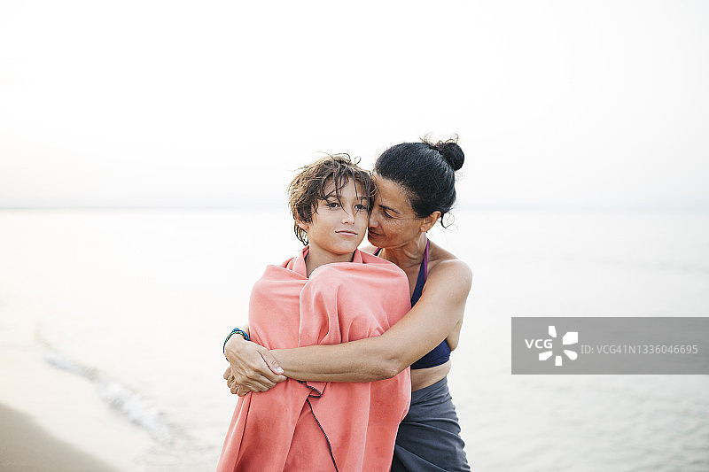 一个女人和她的儿子在海滩上拥抱图片素材