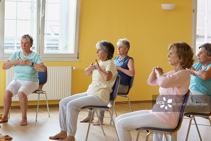 活跃的老年妇女:坐在椅子上的瑜伽课图片素材