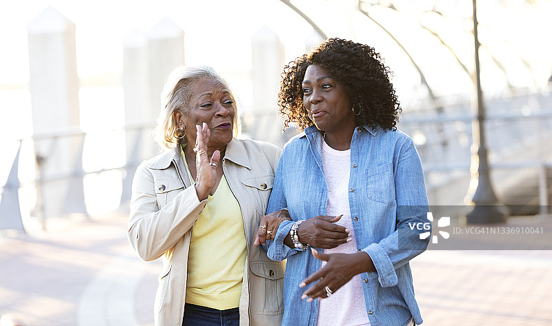 非裔美国妇女走在路上手挽着手交谈图片素材