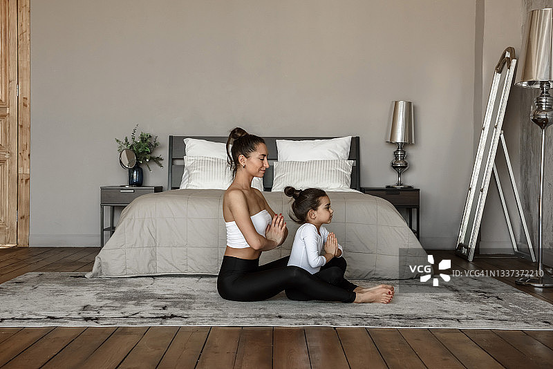 母亲和女儿早上一起在家练习瑜伽冥想图片素材