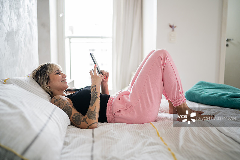中年女性躺在床上玩手机图片素材