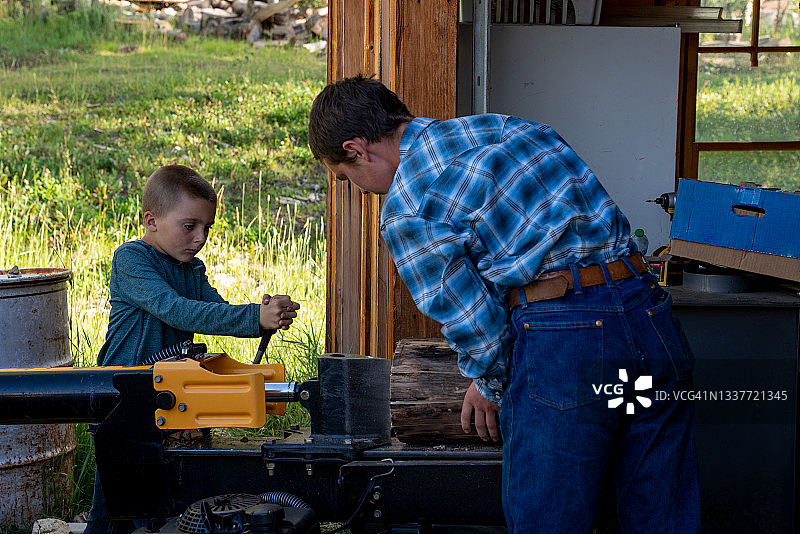在科罗拉多州特柳赖德附近的洛矶山脉和洛矶山脉西南部的一个牧场上，两兄弟正在用劈柴机劈柴，为即将到来的冬天储存柴火图片素材